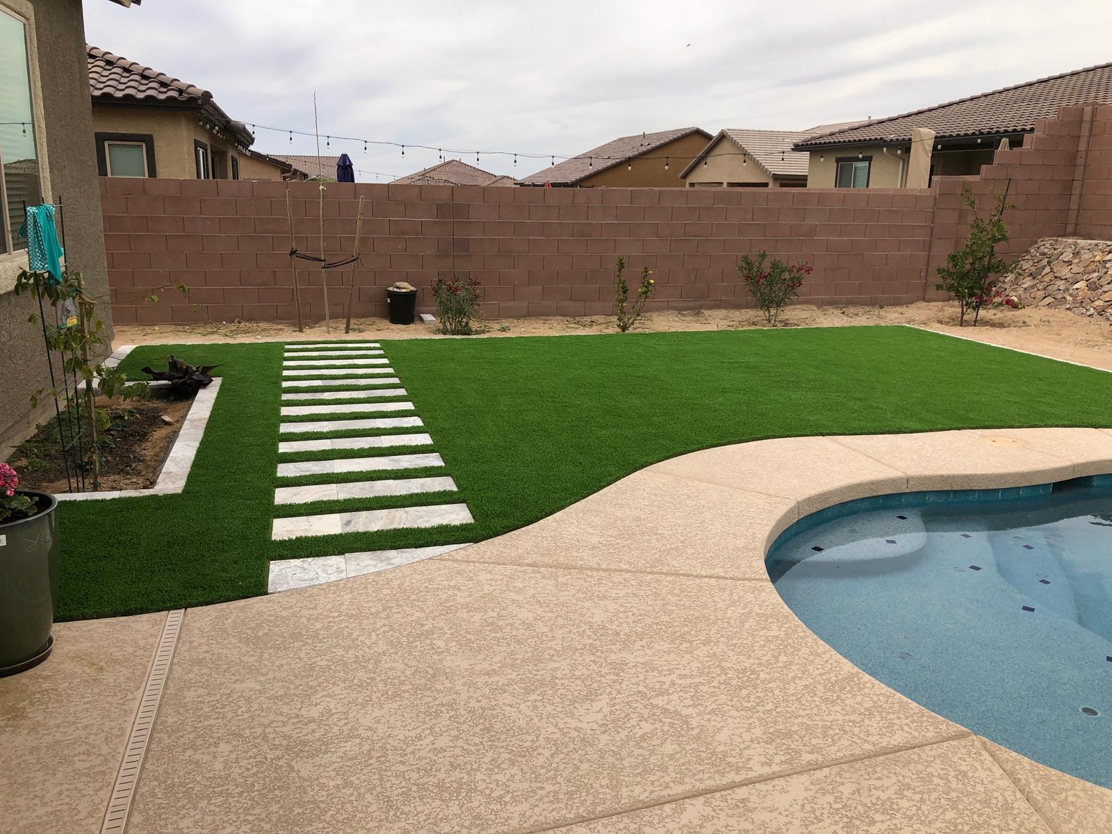 Striped artificial grass installation around a backyard pool in Phoenix Arizona